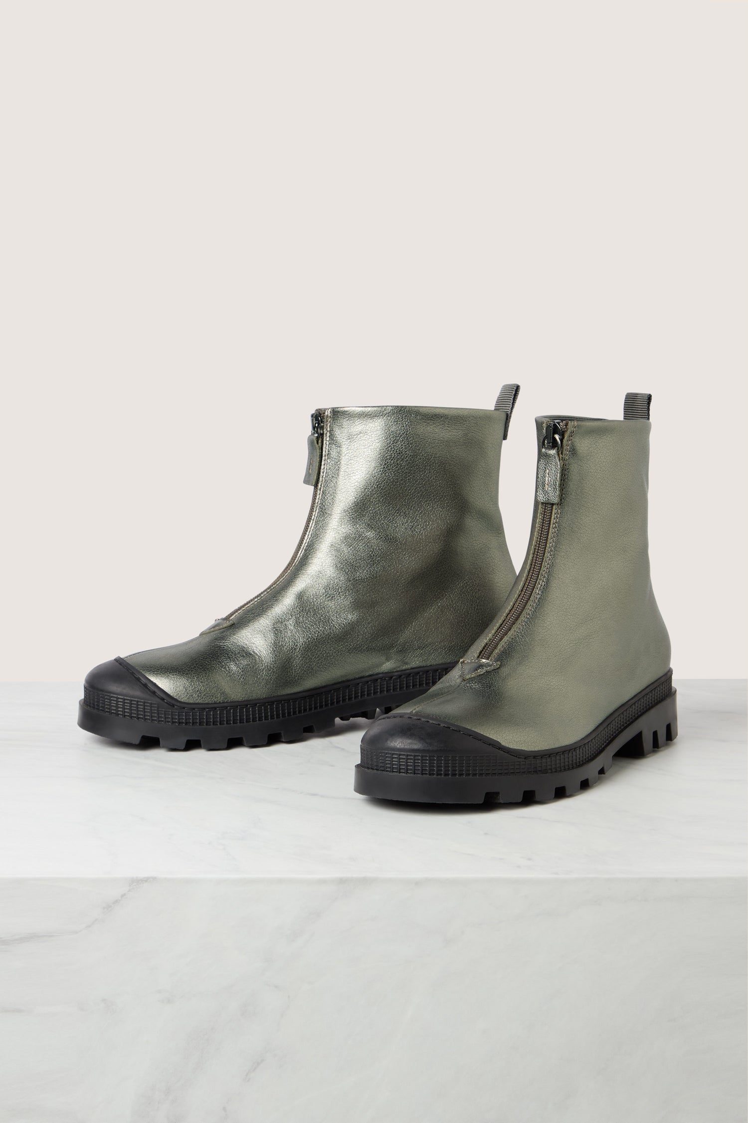 A pair of metallic green zip front leather boots by Lofina, featuring black rubber soles and round toes, displayed on a light-colored surface.