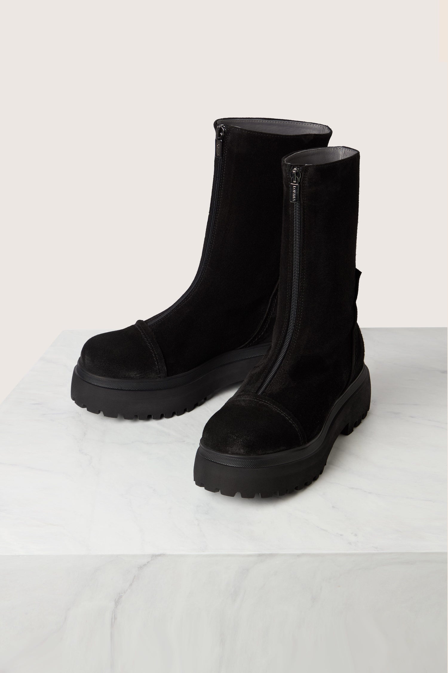 A pair of Zip Front Suede Platform Boots in black, crafted from calfskin suede with thick rubber soles, side zippers, and round toes, displayed on a marble surface with a light gray background.