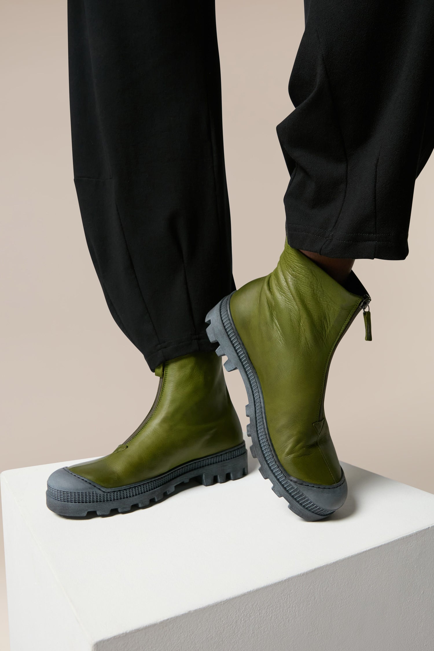 A man is standing on a pedestal wearing Zip Front Boots.