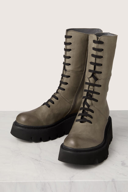 A pair of Platform Lace Up Leather Boots, showcasing exquisite Italian craftsmanship, elegantly resting on a luxurious marble floor.