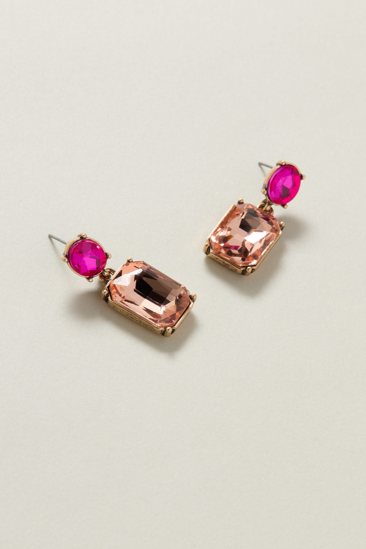 The Twin Gemstone Earrings are a luxurious pair that showcase pink and ruby-colored rectangular gemstones, elegantly set in gold-tone metal, making them perfect for those who appreciate fine craftsmanship.