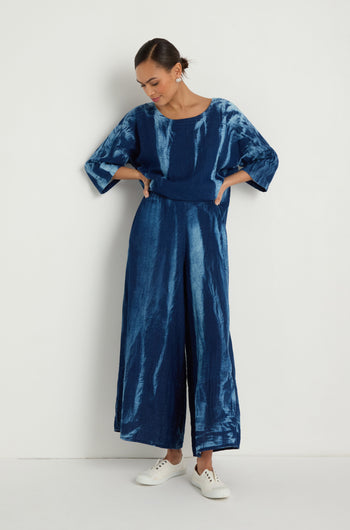 Woman wears Soft Denim Pocket Trousers with a loose-fitting, tie-dye blue top and white sneakers, standing against a plain white background.