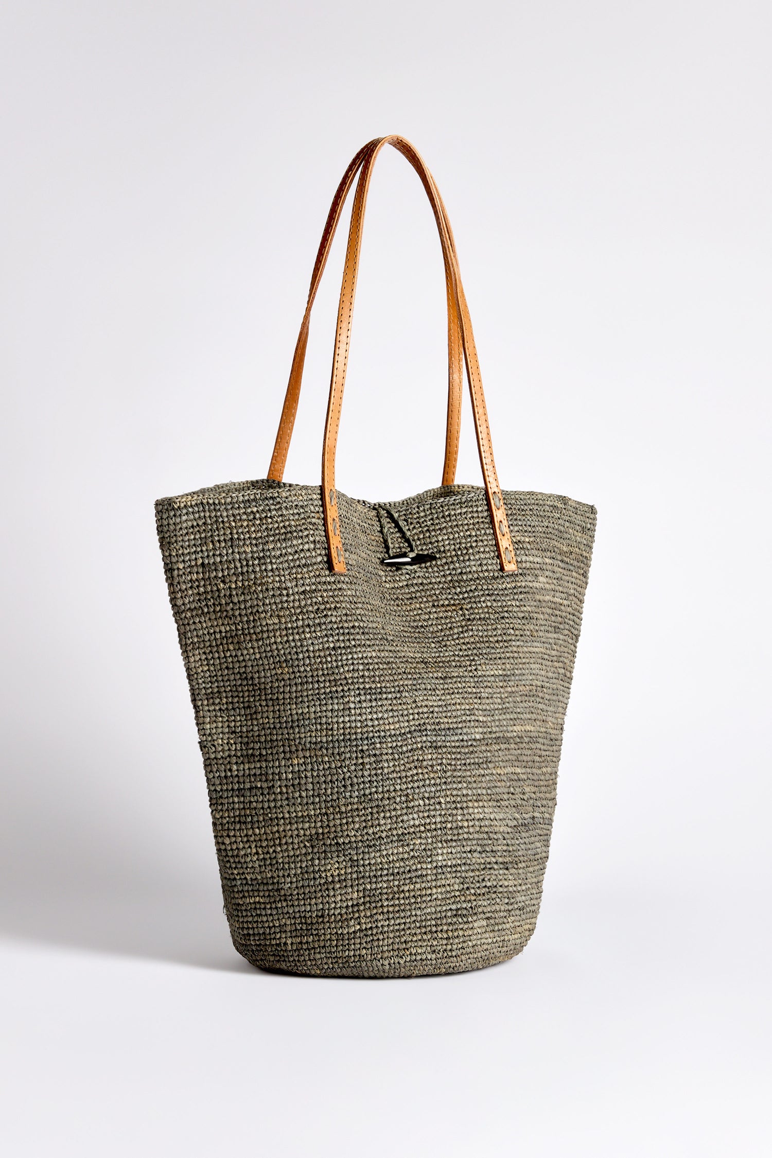 A gray textured tote with brown leather handles, akin to the Ilana Raffia Basket, rests elegantly on a plain white background.