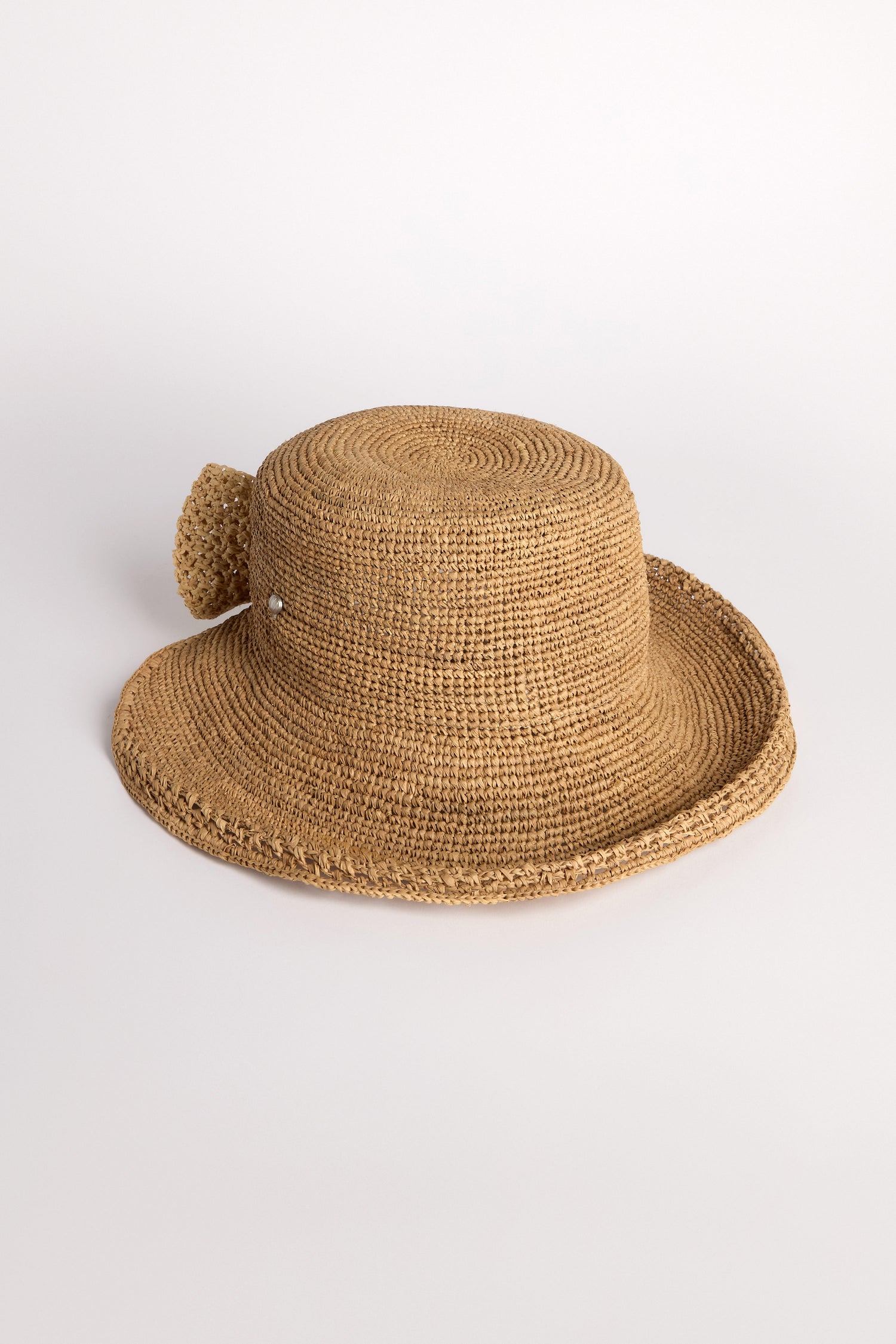 The Chapeau Noloa, a natural woven straw hat with a wide brim, effortlessly exudes summer style against a plain background.