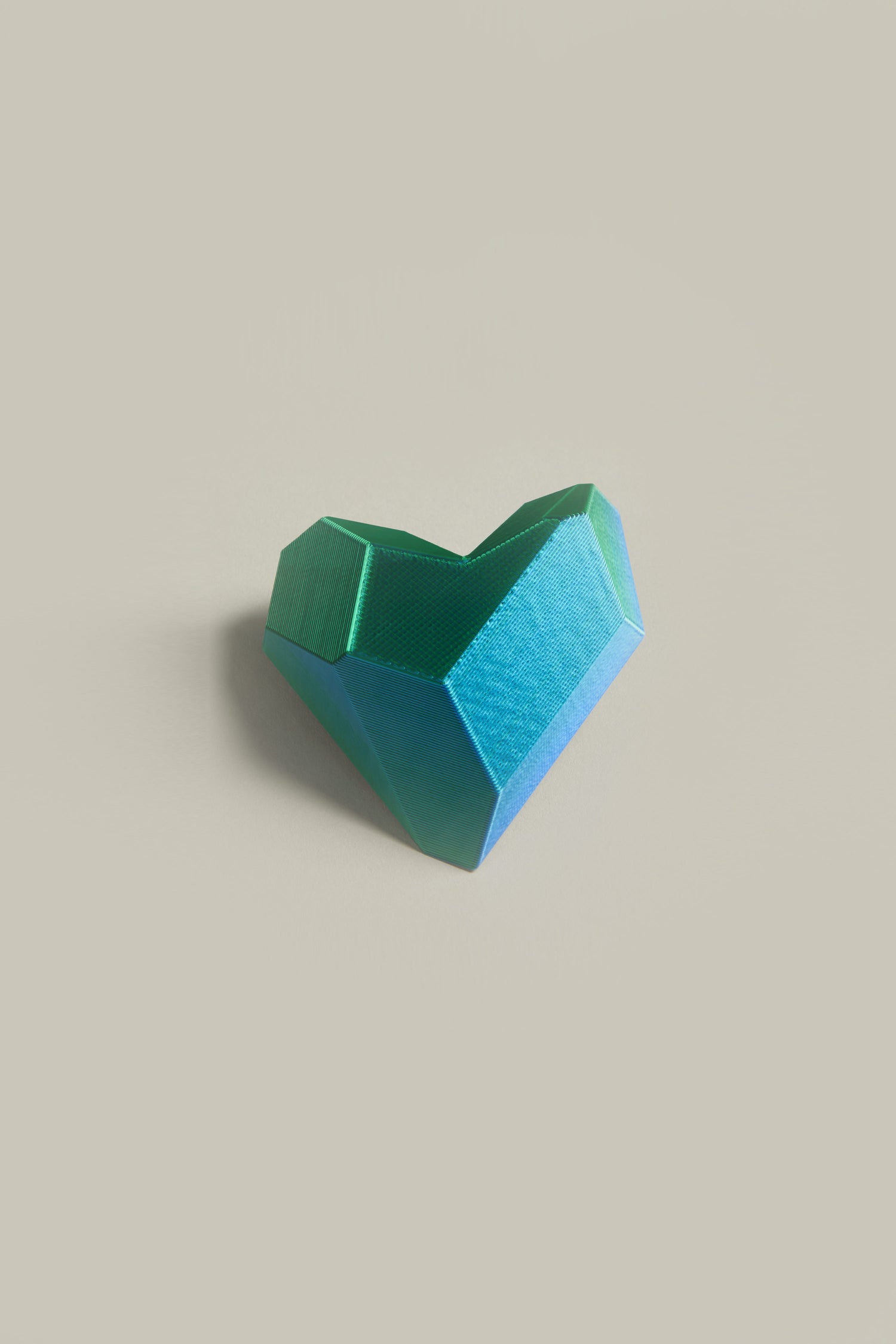 A 3D Printed Heart Brooch in turquoise and green stands out against a light gray background, highlighting contemporary accessory design with cutting-edge 3D printing technology.