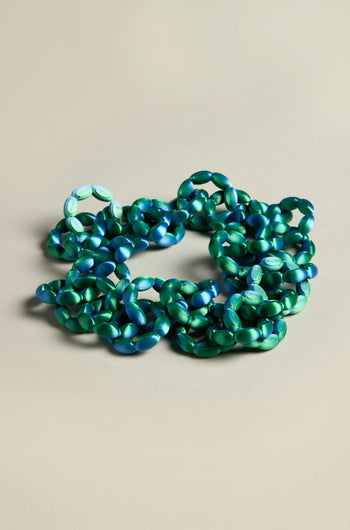 A 3D Printed Links Necklace featuring green and blue interlocking chain links is set against a neutral background. Its ultra-lightweight design reflects the innovative style of Maison 203.