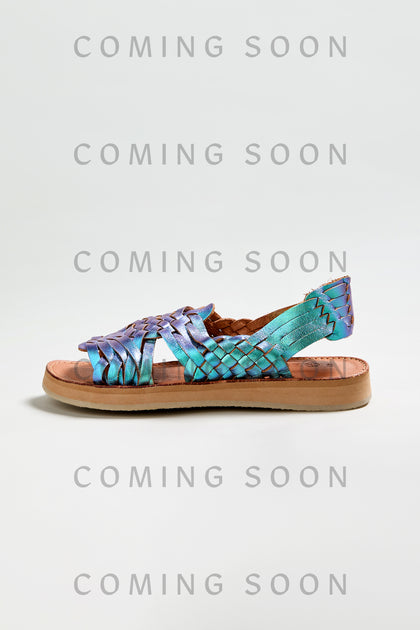 The Camila Mermaid Woven Sandal, featuring an iridescent strap and tan sole, is showcased on a light gray background with "COMING SOON" text, emphasizing its online exclusive status.