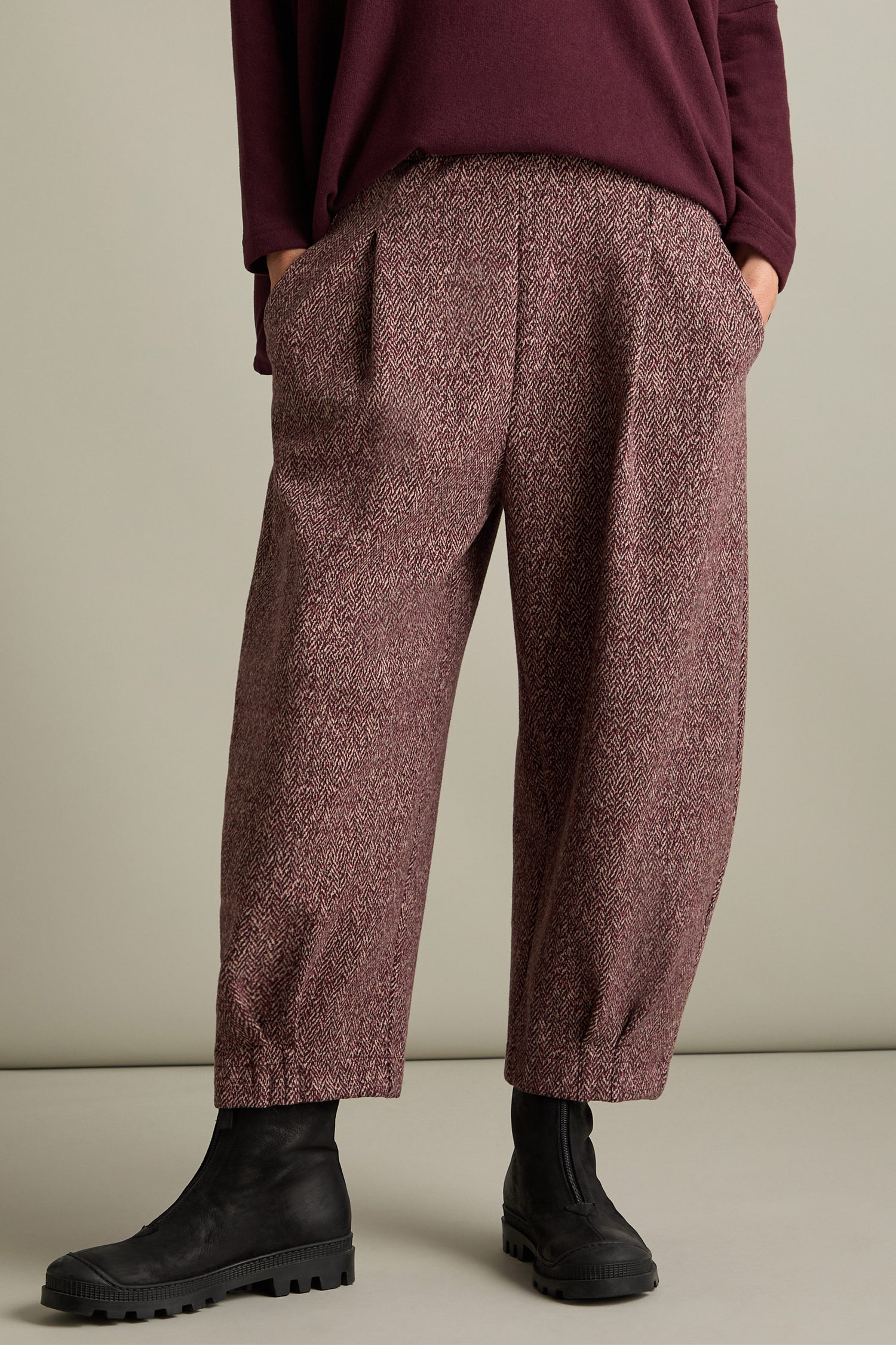 A person wearing Biano Jersey Jacquard Trousers with black boots, with their hands in the pockets of the pants, showcasing Italian craftsmanship.