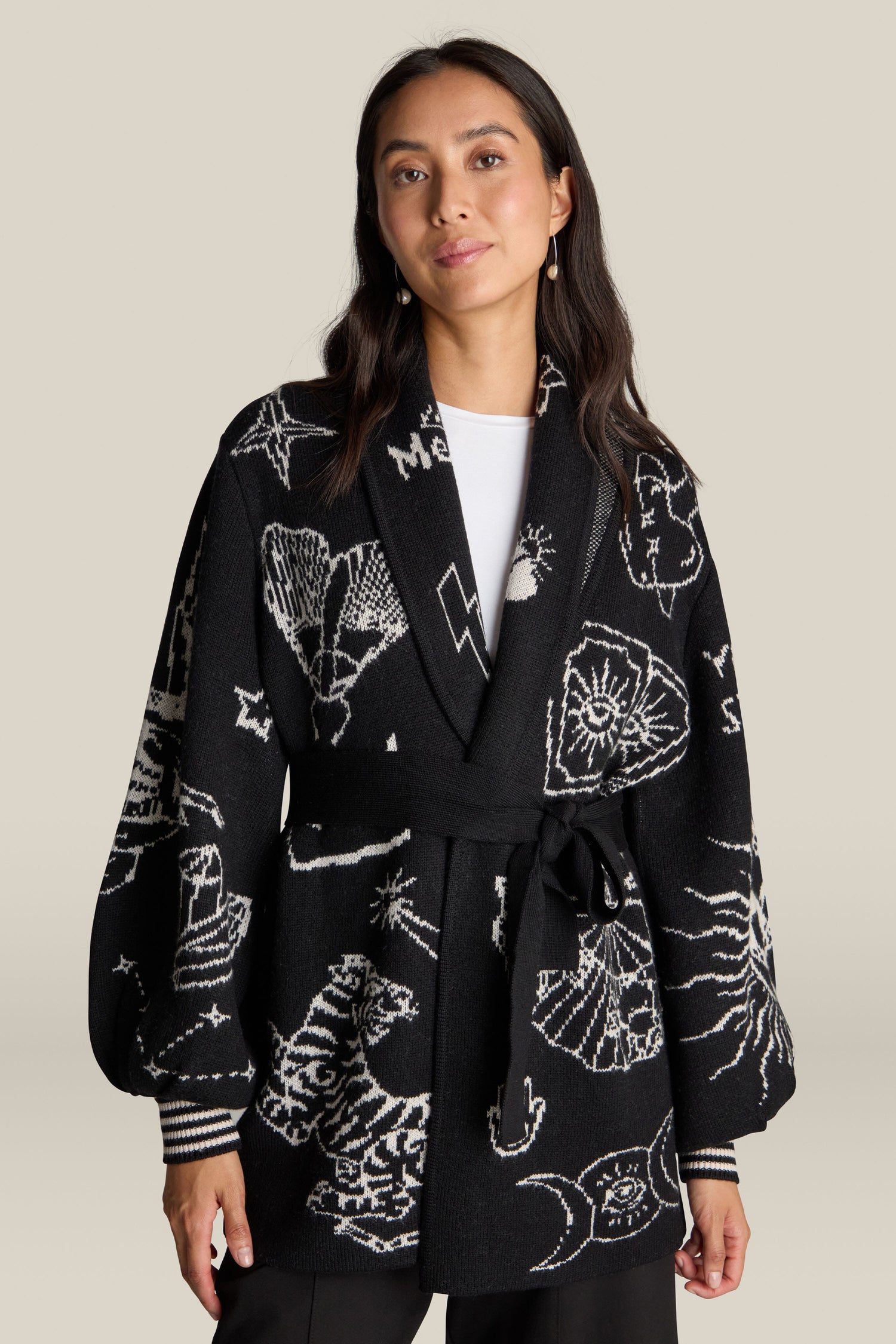 Against a neutral background, a woman stands wearing the Barbara Long Cardigan, crafted from 100% wool and adorned with mystical celestial and nature motifs.