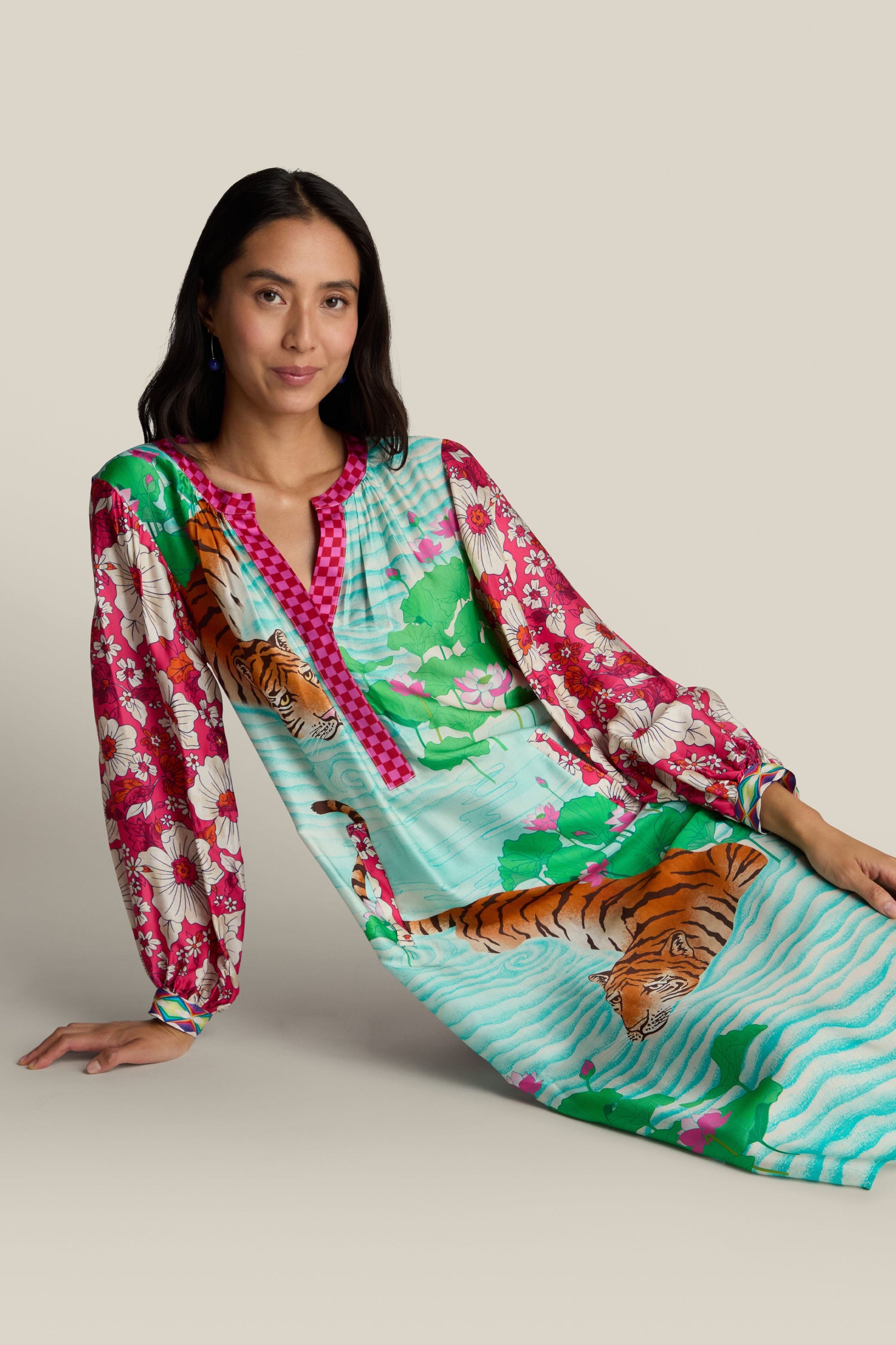 A woman wearing the Twisted Love Hanna Placket Dress, featuring vibrant floral patterns and striking tiger illustrations, poses against a plain background.