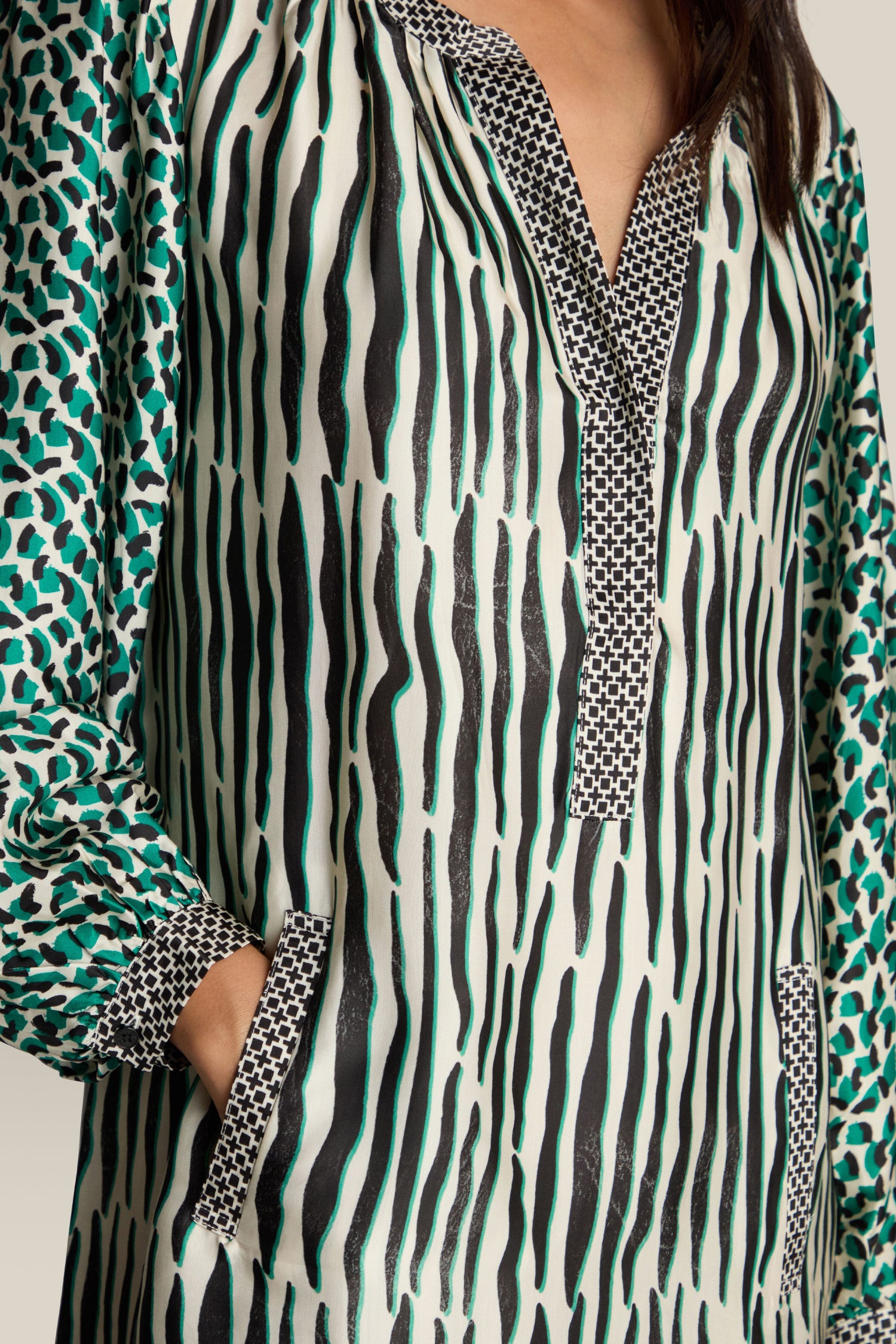 A person wearing the statement Tropical Hanna Placket Dress with zebra stripes and green spots, featuring a split neckline and convenient pockets.