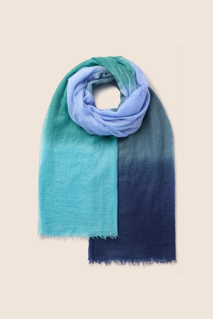 A St Tropez Cashmere Shawl, transitioning from light blue to dark blue, draped in a loop.