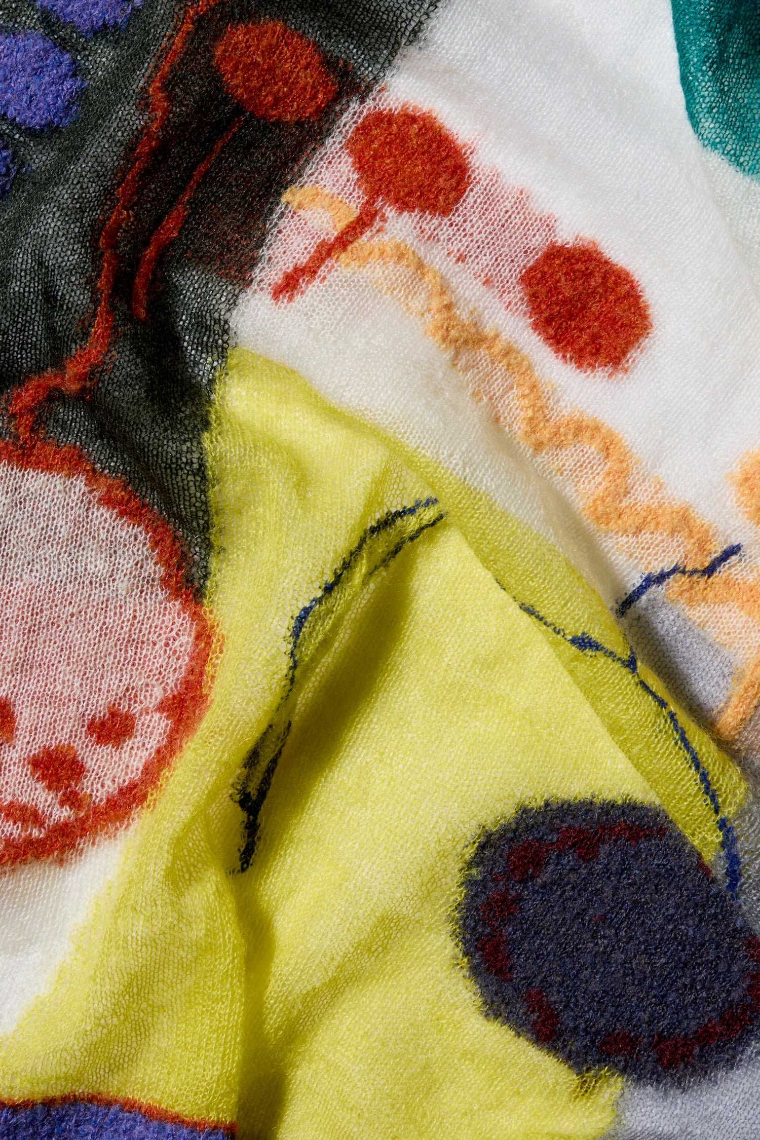 Close-up image of the Abstract Mohair Shawl by M.&Kyoko, featuring a stunning array of vibrant patterns and shapes in yellow, red, black, and green. This luxurious mohair shawl is more than just fabric; it's a wearable art piece that lends an elegant touch to any outfit.