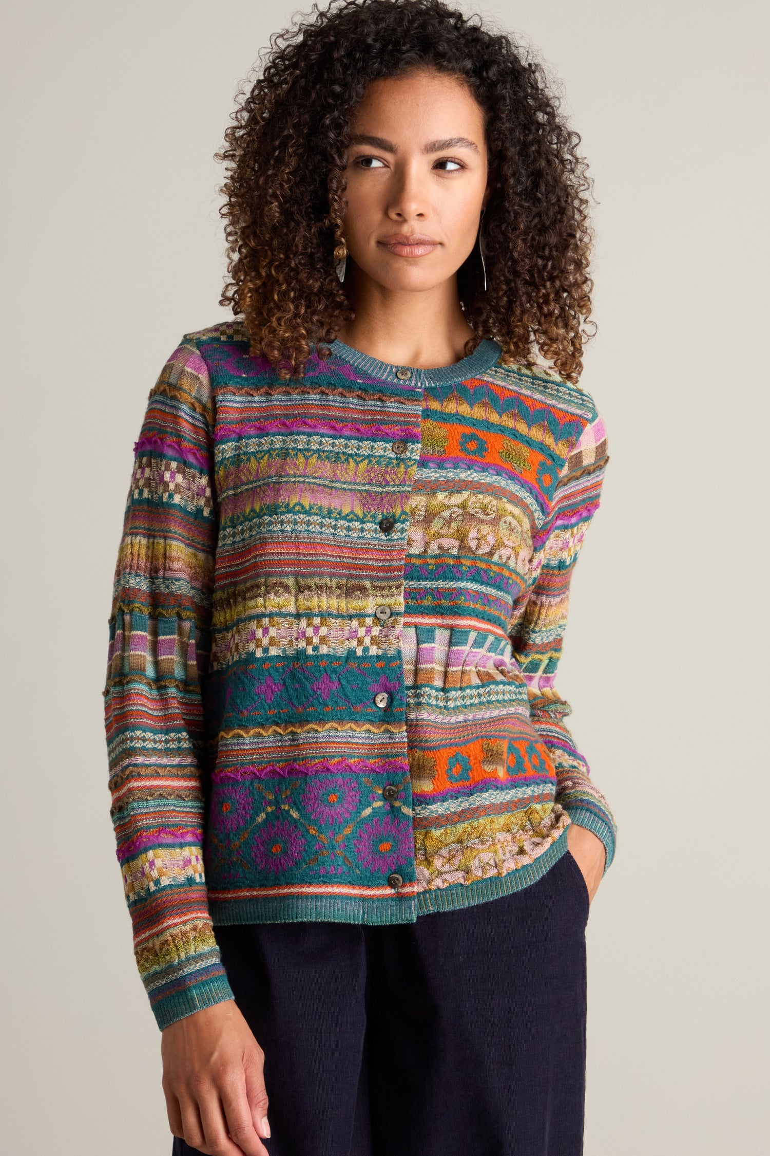 Person wearing a Round Neck Button Cardigan with a colorful intarsia knit design and dark pants, standing against a plain background.