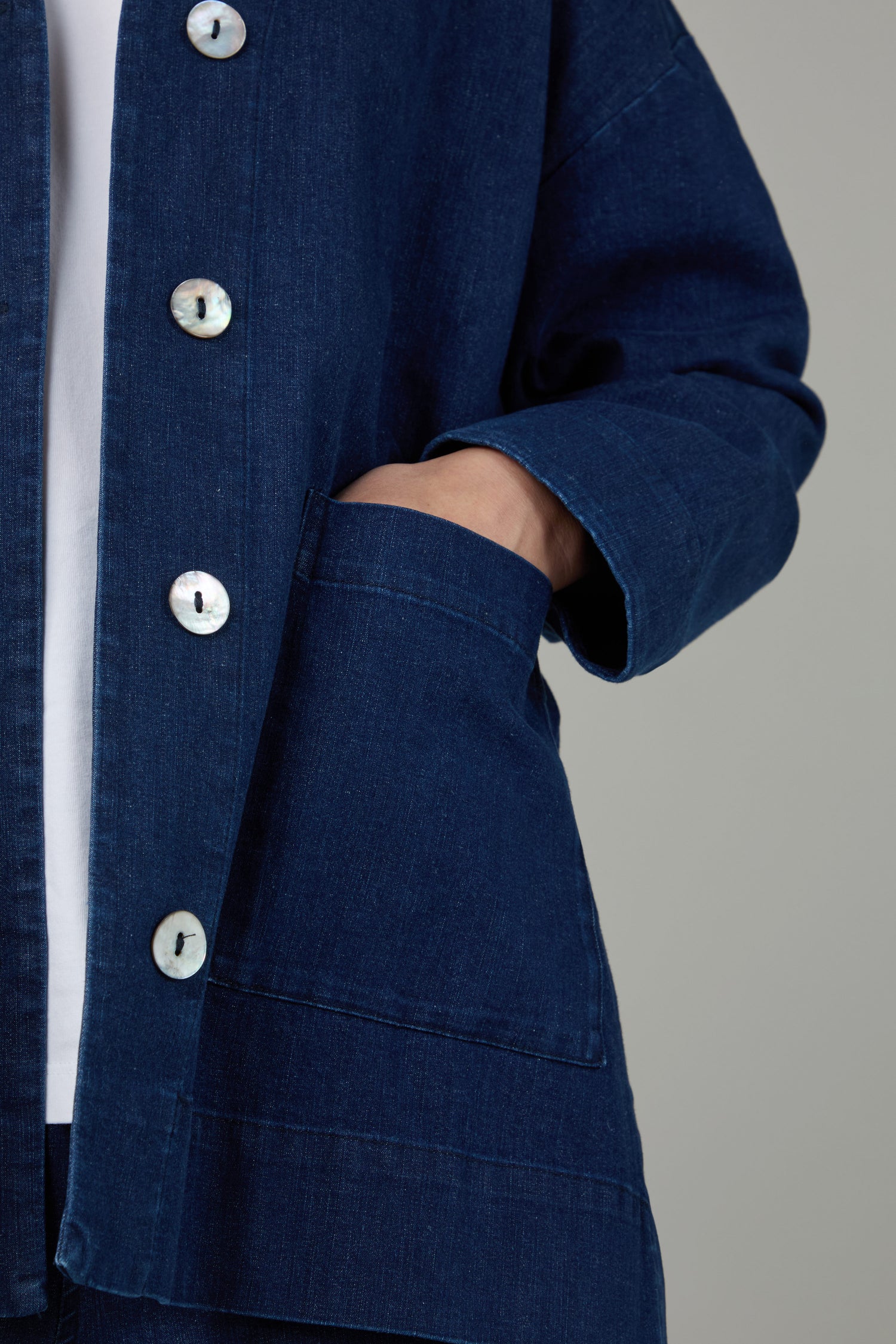 A person wearing the Stretch Denim Boxy Jacket in a deep indigo wash with large buttons has one hand tucked into the front pocket.