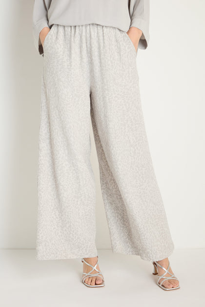 Wearing Animal Textured Jacquard Wide Trouser in light gray, a matching top, and white sandals, a person stands with hands in pockets against a plain background.