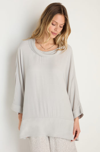 A woman wears the Crepe Boxy Top, a loose-fitting light gray long-sleeve style with cuffed sleeves (MTT5245-LVC), standing against a plain white background.