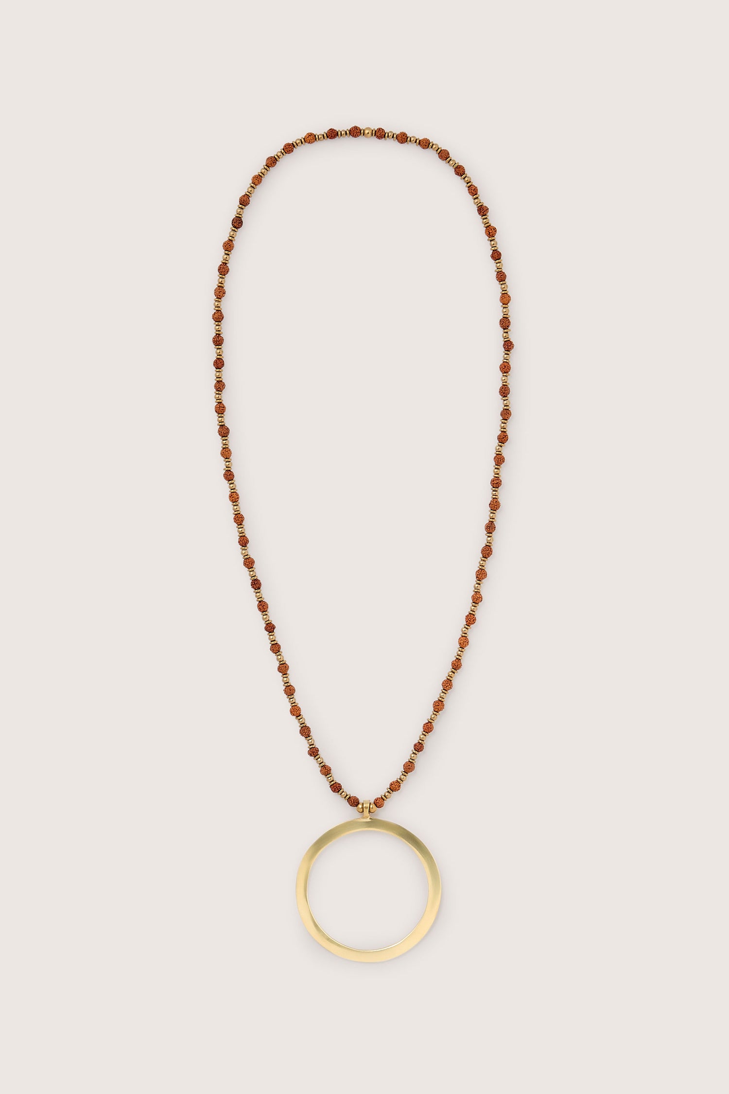 The Circle Pendant Necklace features small red and gold beads with a striking large gold circle pendant hanging in the center.