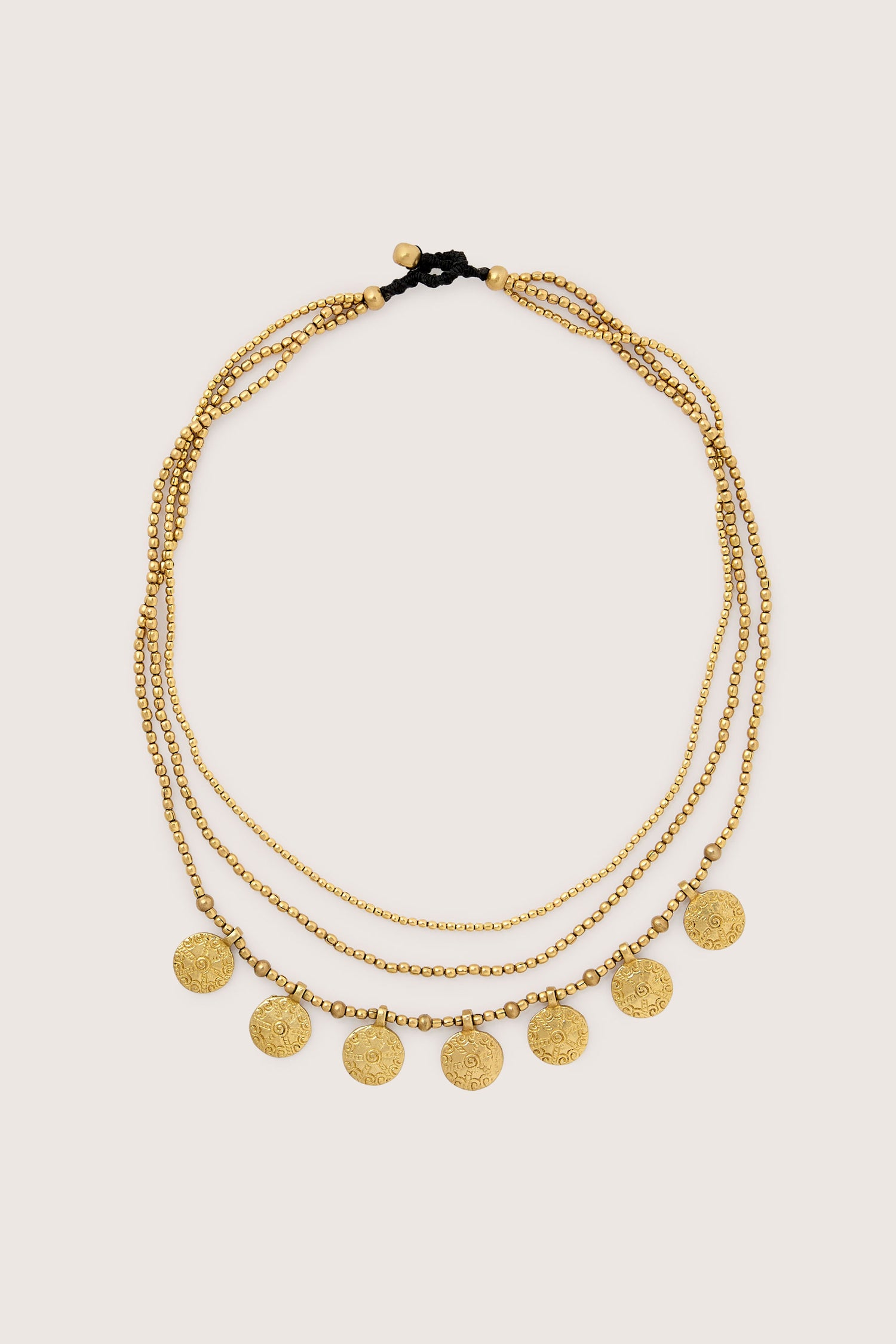 The Chakra Necklace is a gold layered necklace that features multiple strands with seven small coin-like chakra pendants and delicate beads.