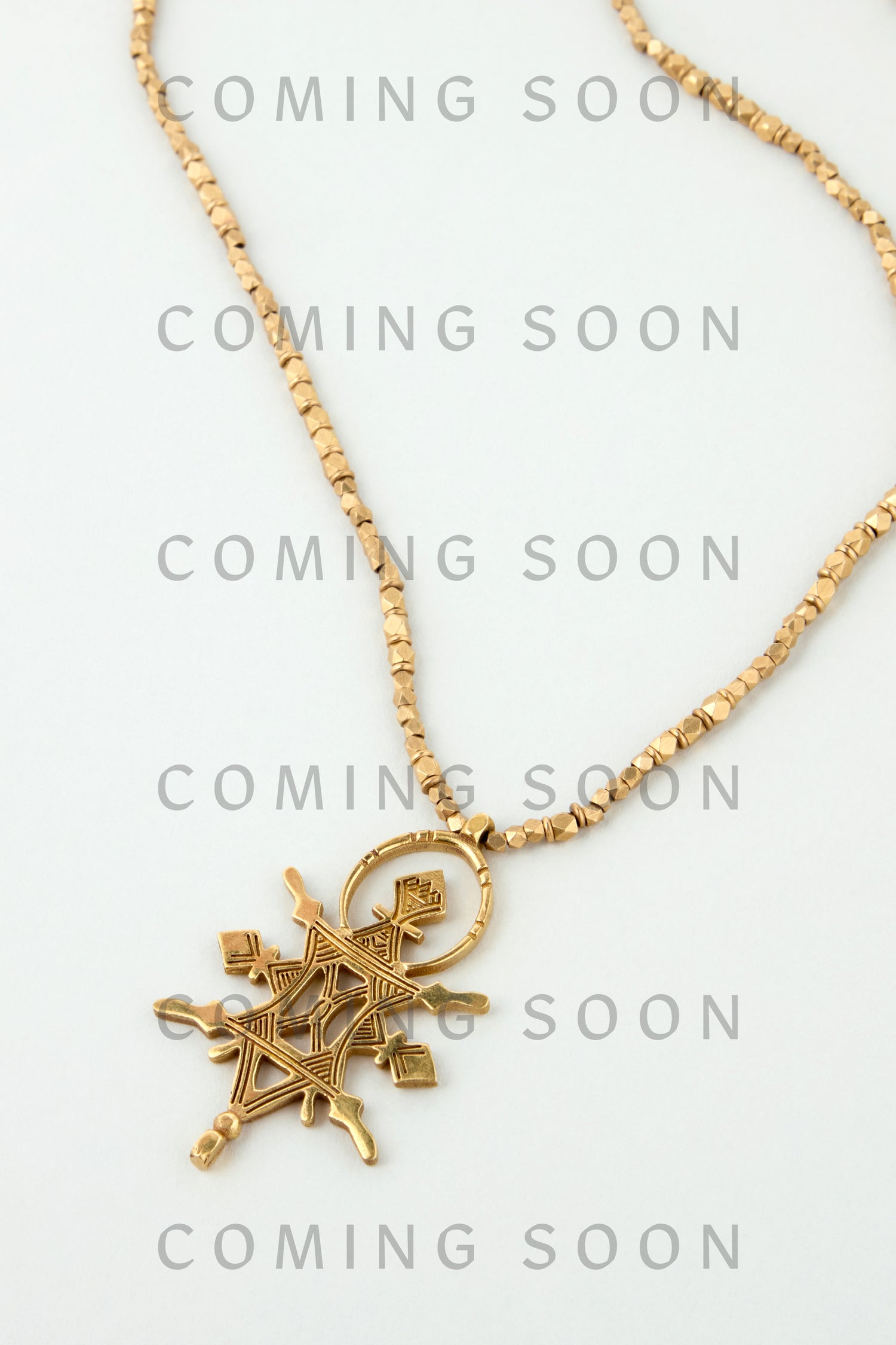 A gold Abalak Pendant necklace is displayed on a light background with "COMING SOON" repeatedly overlaid, highlighting this NCCCE487 Online Exclusive.