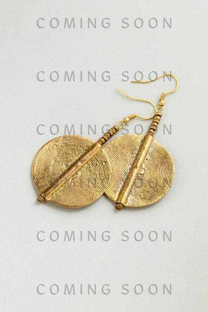 A pair of round, textured gold Spiral Earrings with hook fastenings are displayed on a light background, overlaid with the repeated words "COMING SOON.