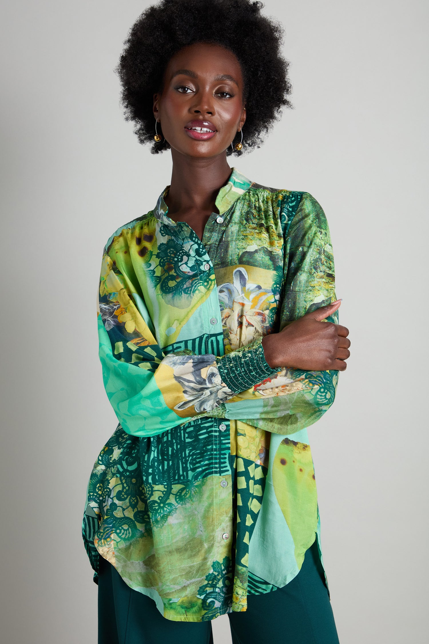 A person wearing a Patchwork Print Viscose Shirt with a stand collar and green pants stands confidently with arms crossed against a plain background.