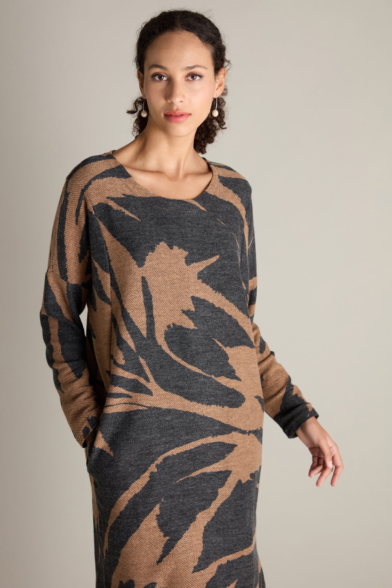 A person wearing the elegant Scoop Neck Jacquard Dress, featuring a striking black and brown patterned design, stands against a plain background.