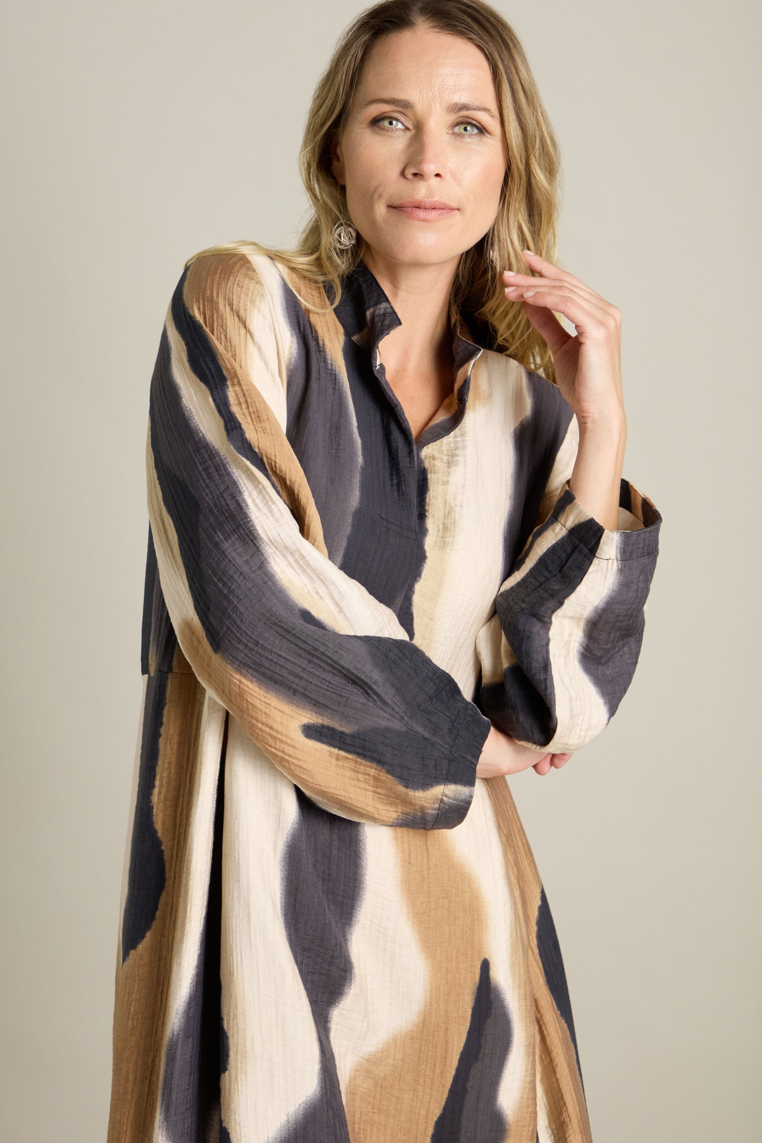 A person wearing a Crinkle Viscose Print Dress with a textured finish and stand-open collar stands against a plain background, looking slightly off-camera.