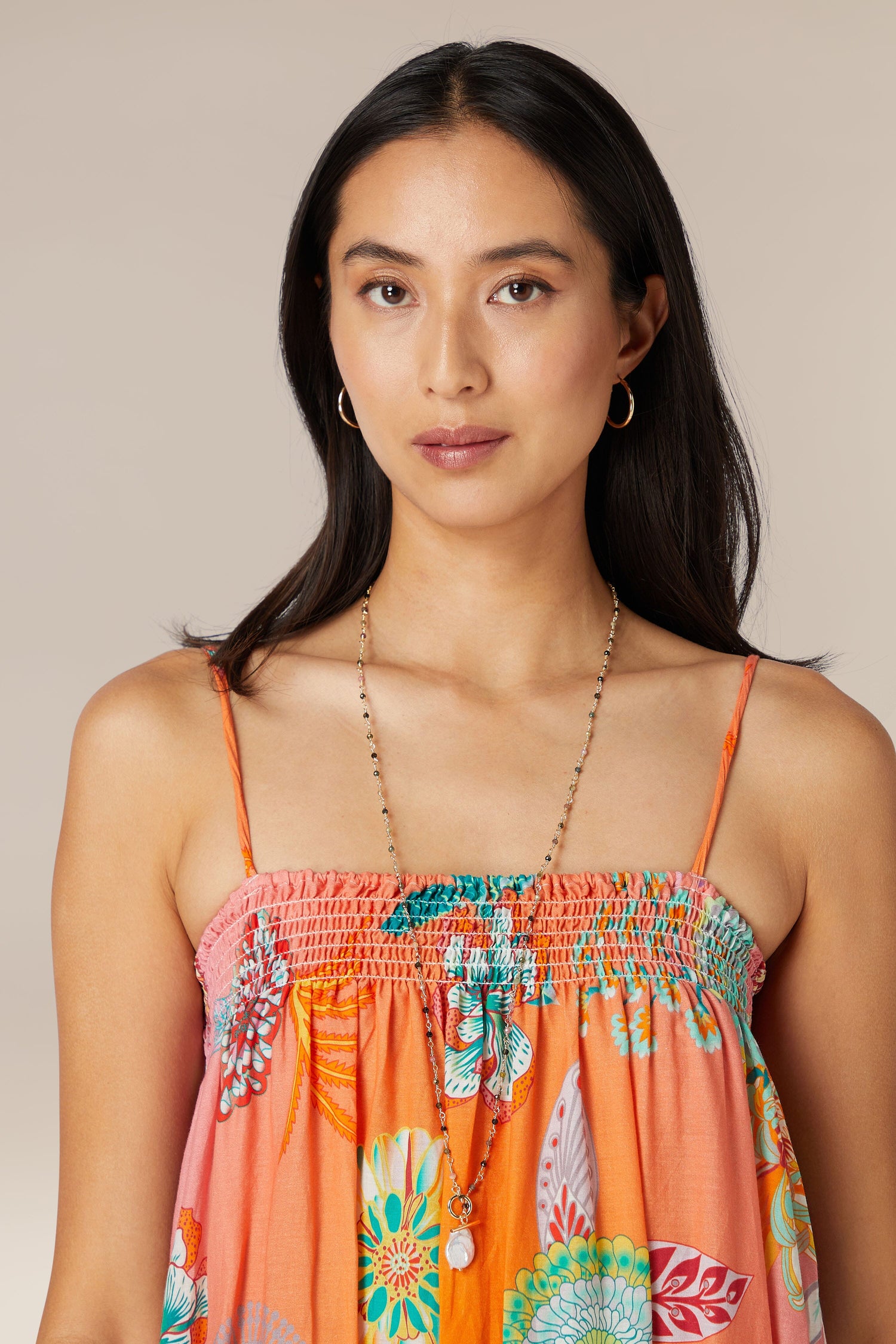 Woman in a floral orange dress posing for a portrait, accented with an elegant Black Diamond Necklace.