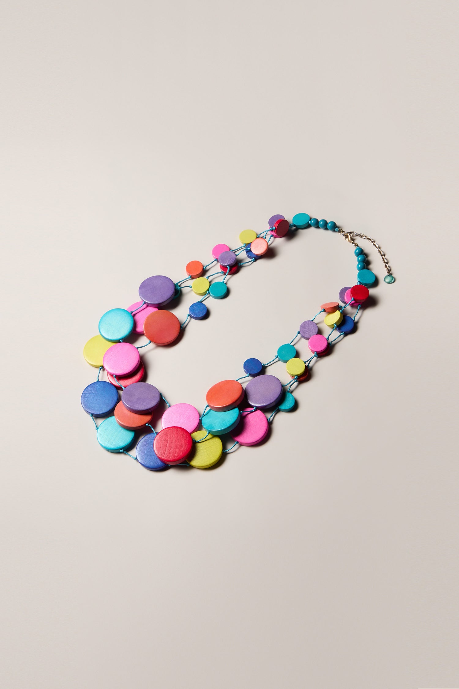 The Cascade Rainbow Spheres Necklace is a lightweight, show-stopping piece featuring large, brightly colored circular beads in shades of pink, blue, purple, and yellow arranged in an overlapping pattern across its multi-strand design.