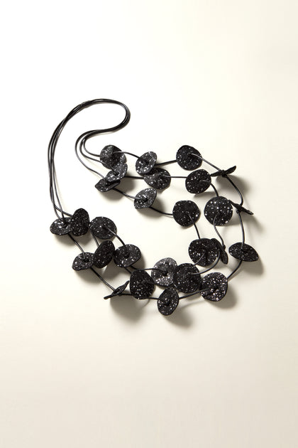 The Painted Petals Necklace showcases a versatile black design adorned with multiple round, flat beads that glitter and are intricately hand-painted for a unique and personalized touch.