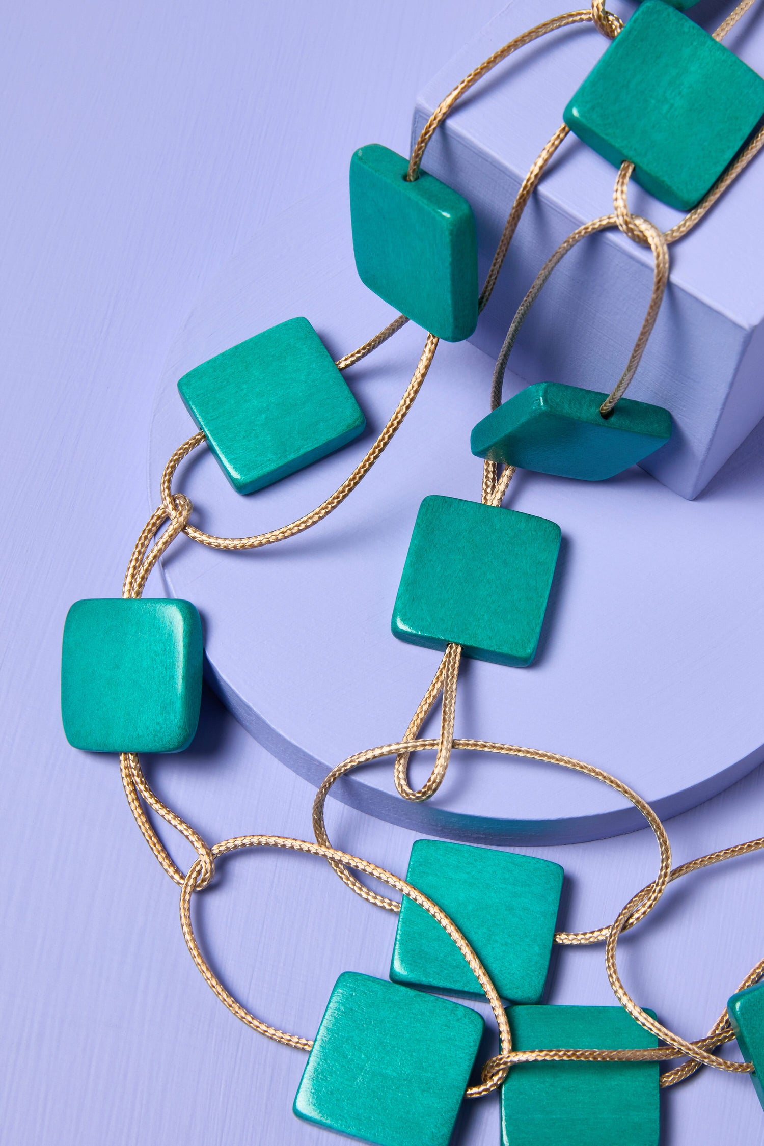 Cascade Squares Necklace displayed over a purple surface.