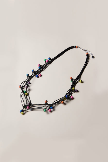 Introducing the Solar System Necklace, a unique accessory featuring multiple black cords adorned with multicoloured wooden beads and finished with a silver clasp.