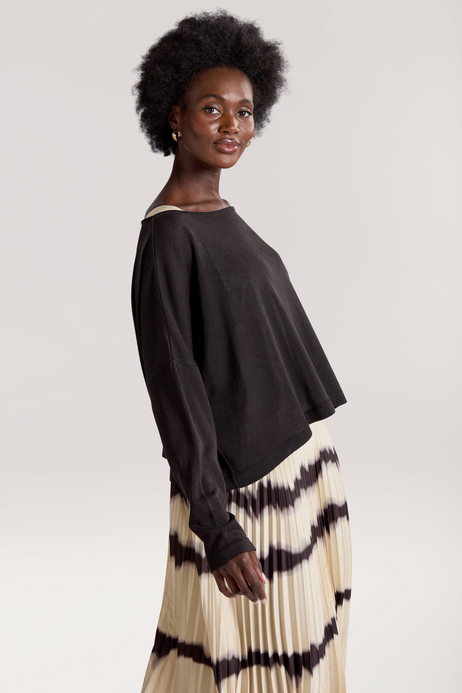 A person with short, curly hair wears a Tie Dye Pleat Dress With Jersey Top. They are standing against a plain background.