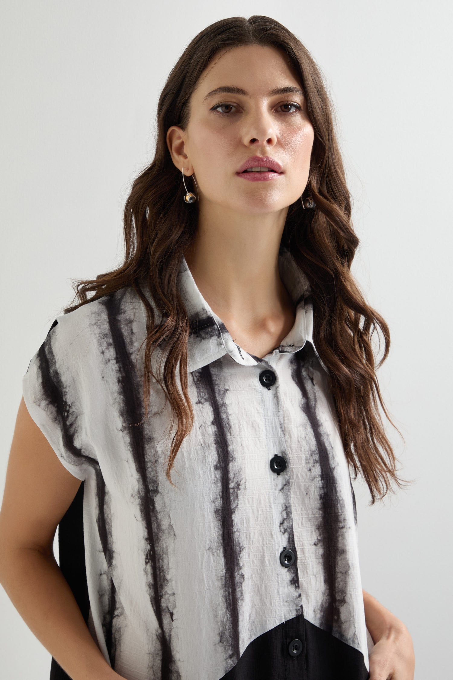 A person with long brown hair wears the Cap Sleeve Button Through Easy Dress, featuring black vertical stripes that resemble a button-up shirt style.