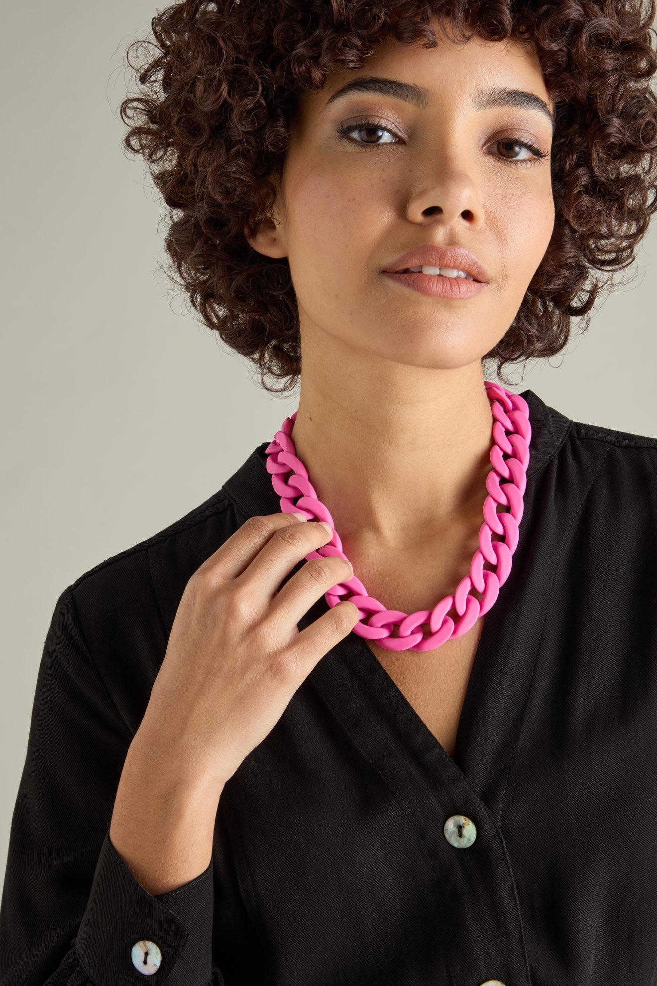 Wearing the Colour Pop Link Necklace, a person in a black top stands out with curly hair framing their neutral expression.