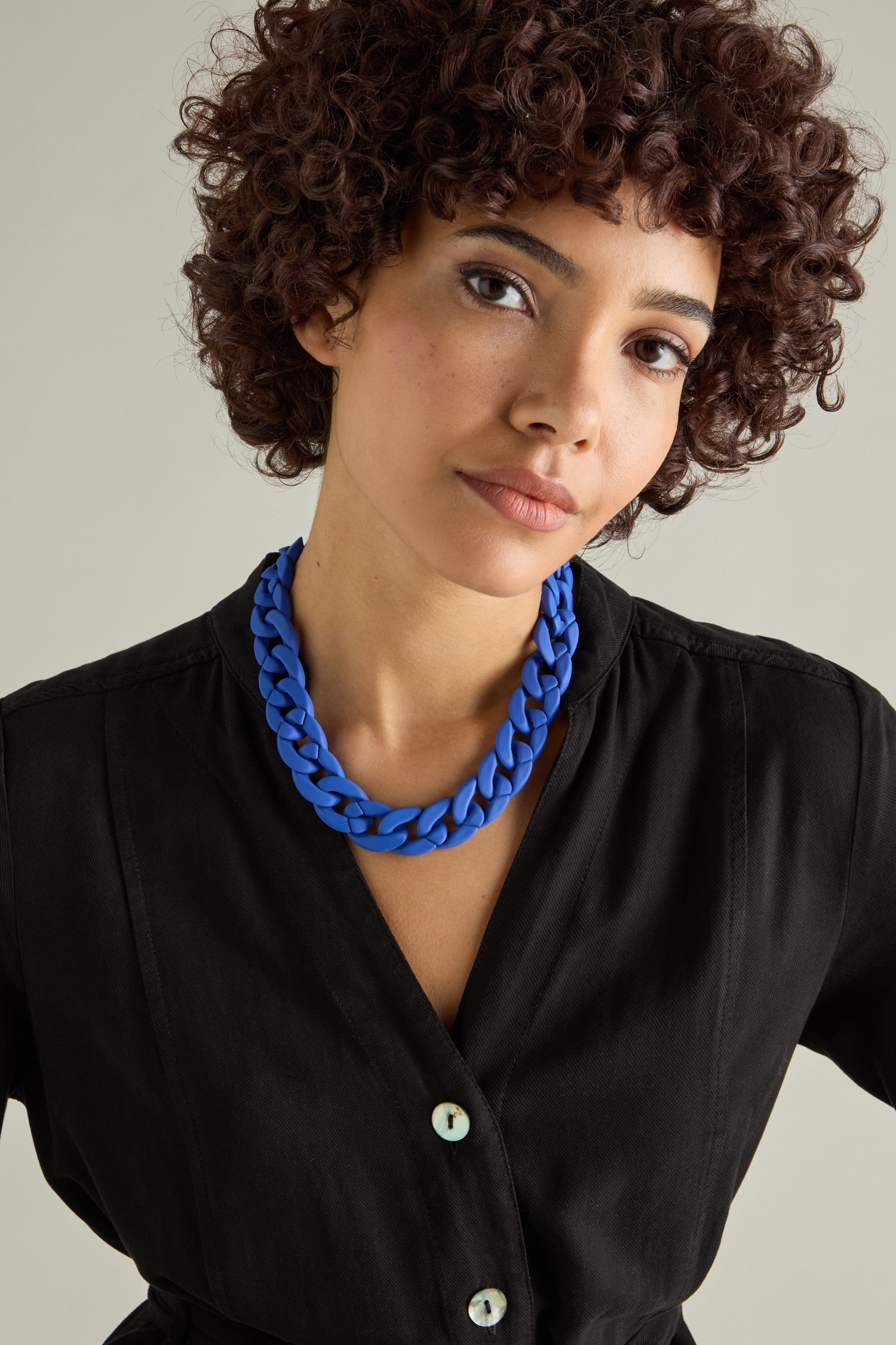 A person with curly hair wears a black buttoned top and the bold, chunky Colour Pop Link Necklace against a plain background.