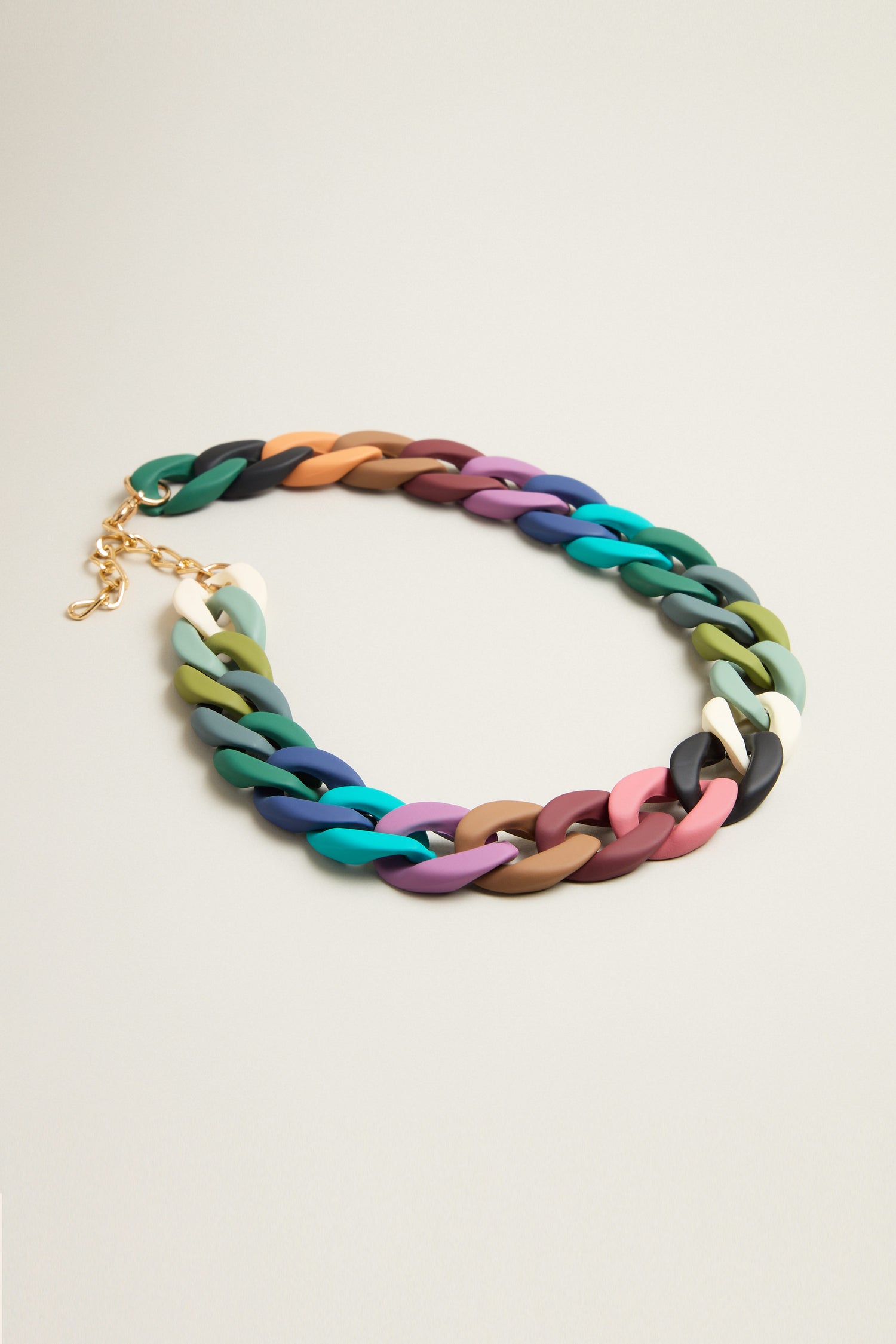 The Colour Pop Link Necklace is a bold accessory featuring vibrant chunky links in teal, pink, brown, and black, accented with a gold clasp.