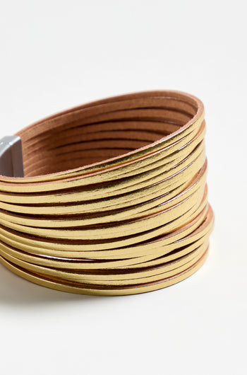 The Vegan Leather Metallic Bracelet boasts multiple slim metallic gold bands wrapped around wide brown vegan leather, creating a striking yet lightweight accessory.