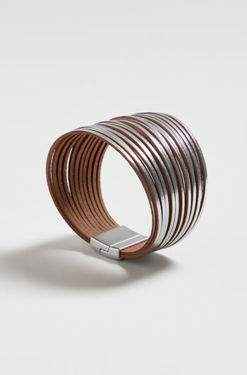 The Vegan Leather Metallic Bracelet features a wide brown vegan leather band, multiple thin silver metallic bands, and a rectangular silver clasp, combining lightweight comfort with modern style. Displayed on a white background.