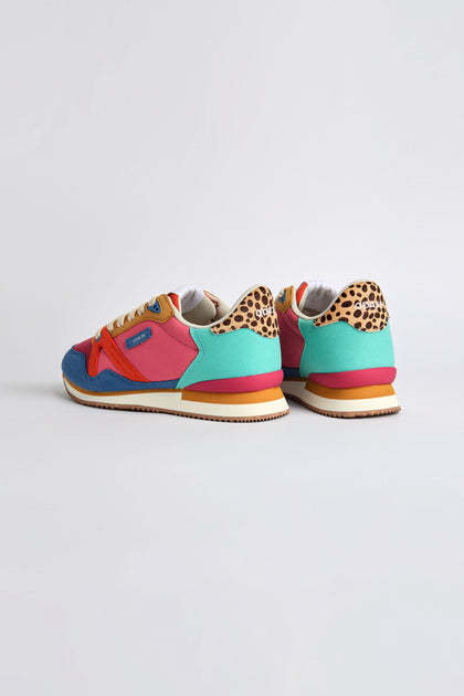 The Andree Trainers, crafted with recycled mesh and vegan suede, feature a colorful design with red, blue, and teal panels and leopard print accents on the heels. They rest elegantly on white soles against a plain white background.