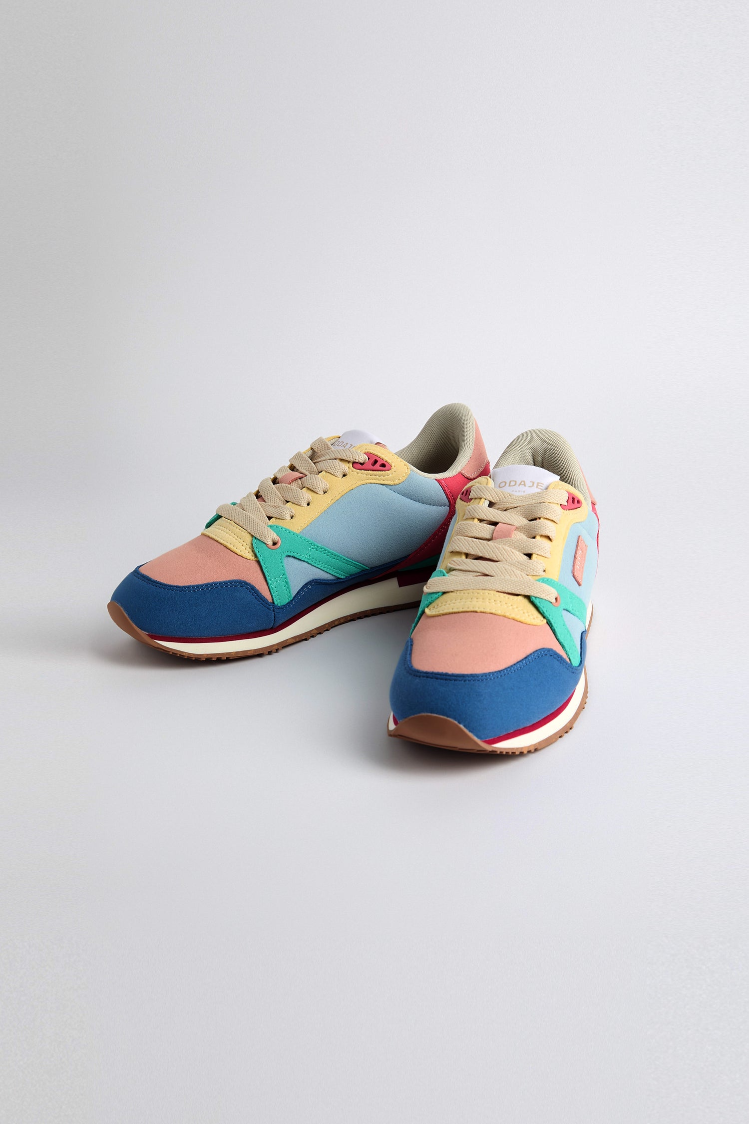 The Andree Trainers are vibrant sneakers showcasing pastel shades of blue, pink, green, and beige. They feature lace-up closures and durable rubber soles made from recycled mesh.