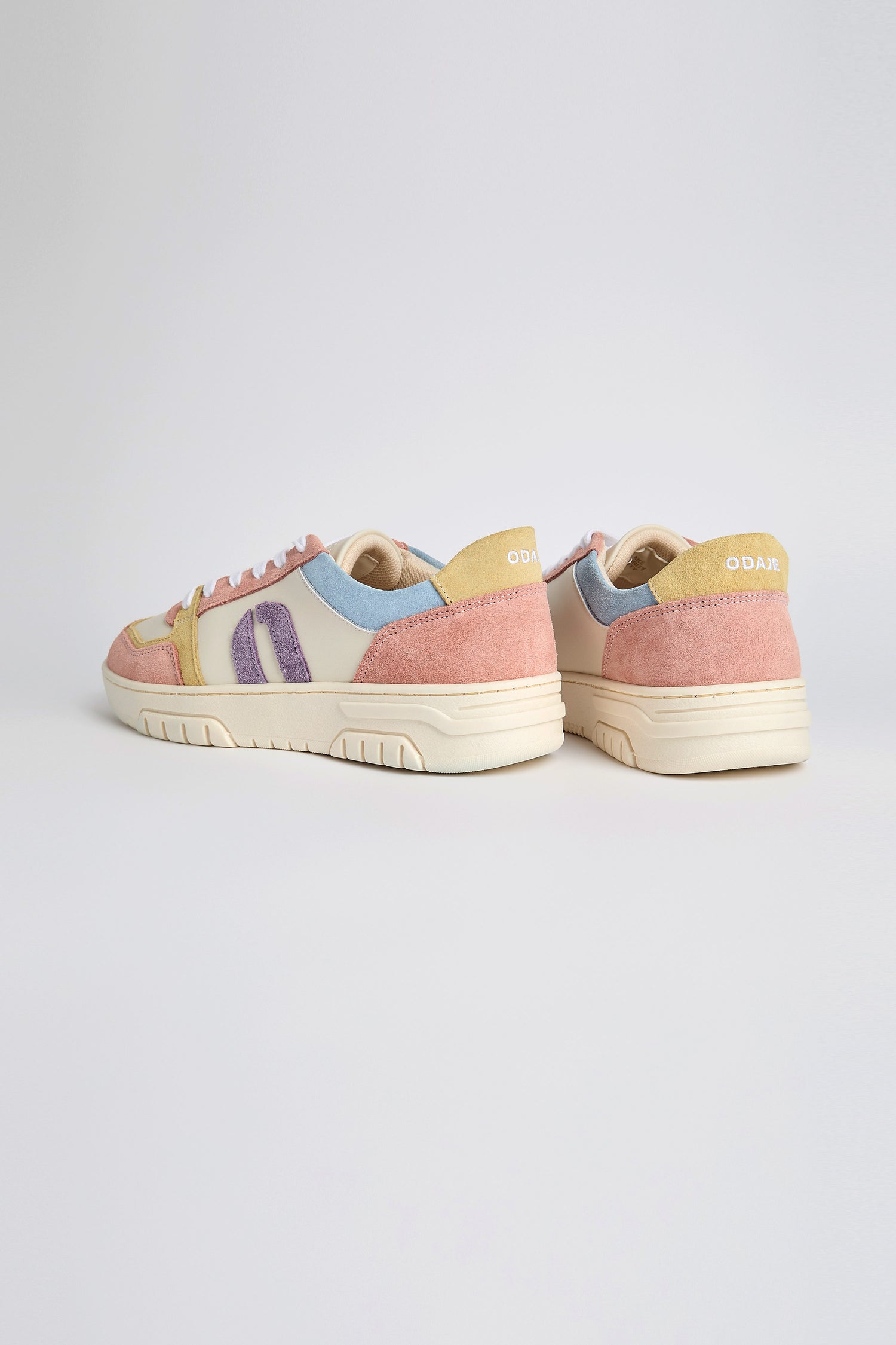 Nora Trainers feature pastel panels and branding on the heel, crafted from vegan suede, and rest gracefully on a light surface.