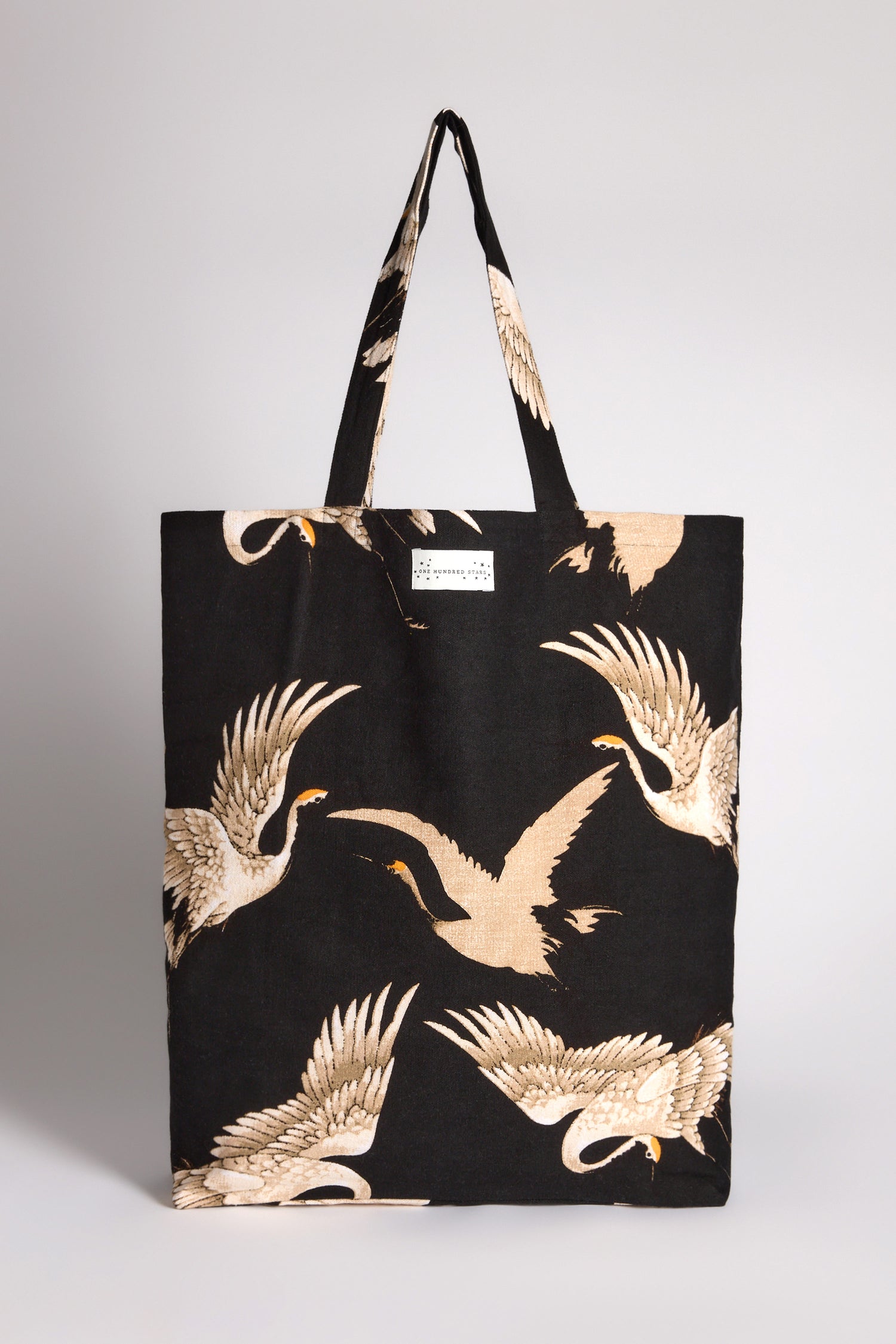 The Stork Canvas Bag is an eco-friendly tote crafted from sustainable cotton, featuring a striking design of beige and white cranes in flight.