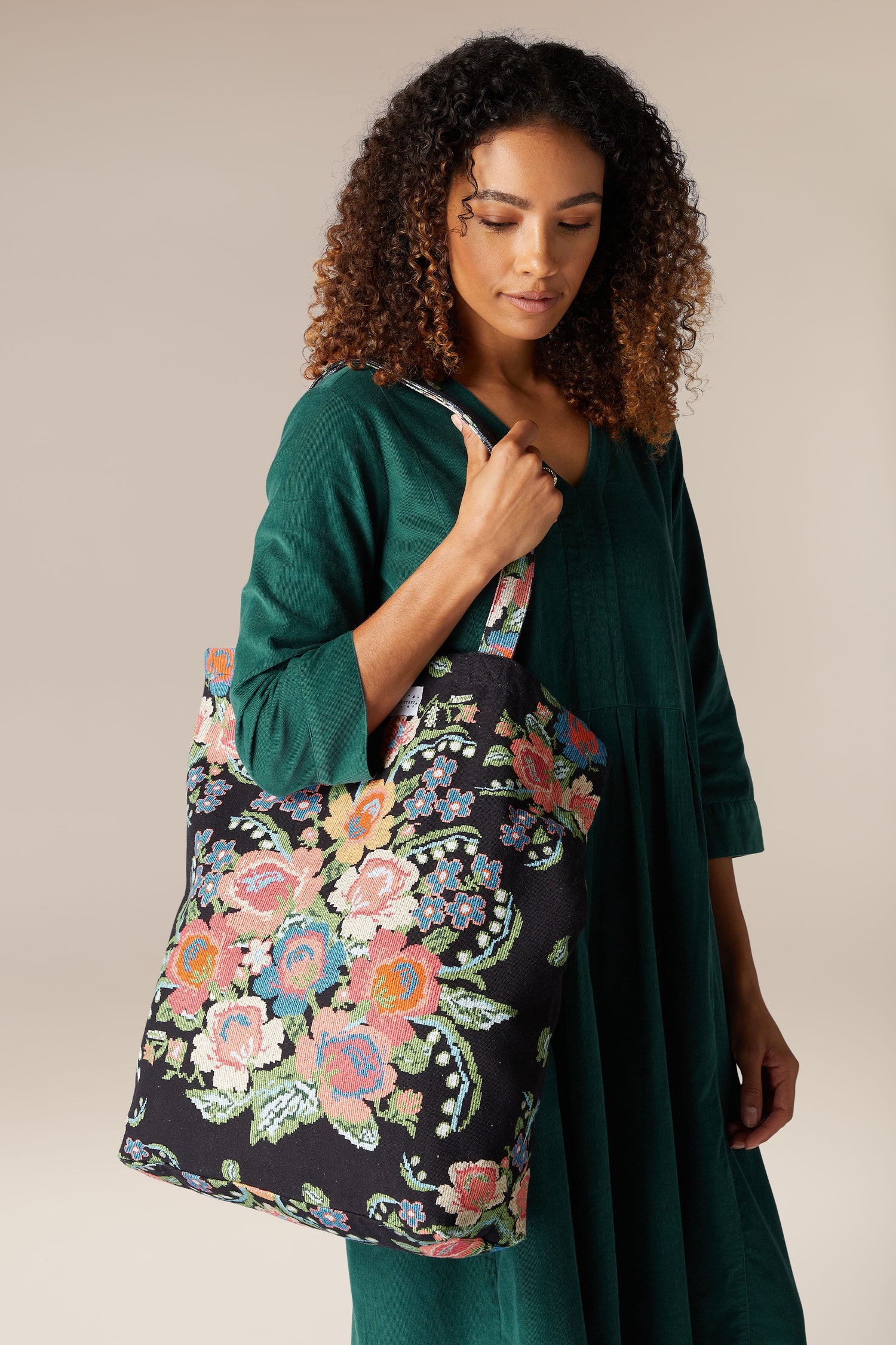 A woman is holding a woven flower canvas bag.