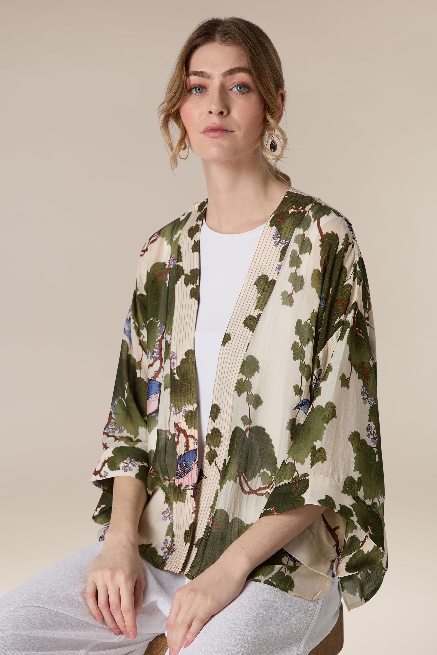 A woman in a luxe design, Japanese Acer Kimono jacket and white top posing against a neutral background.