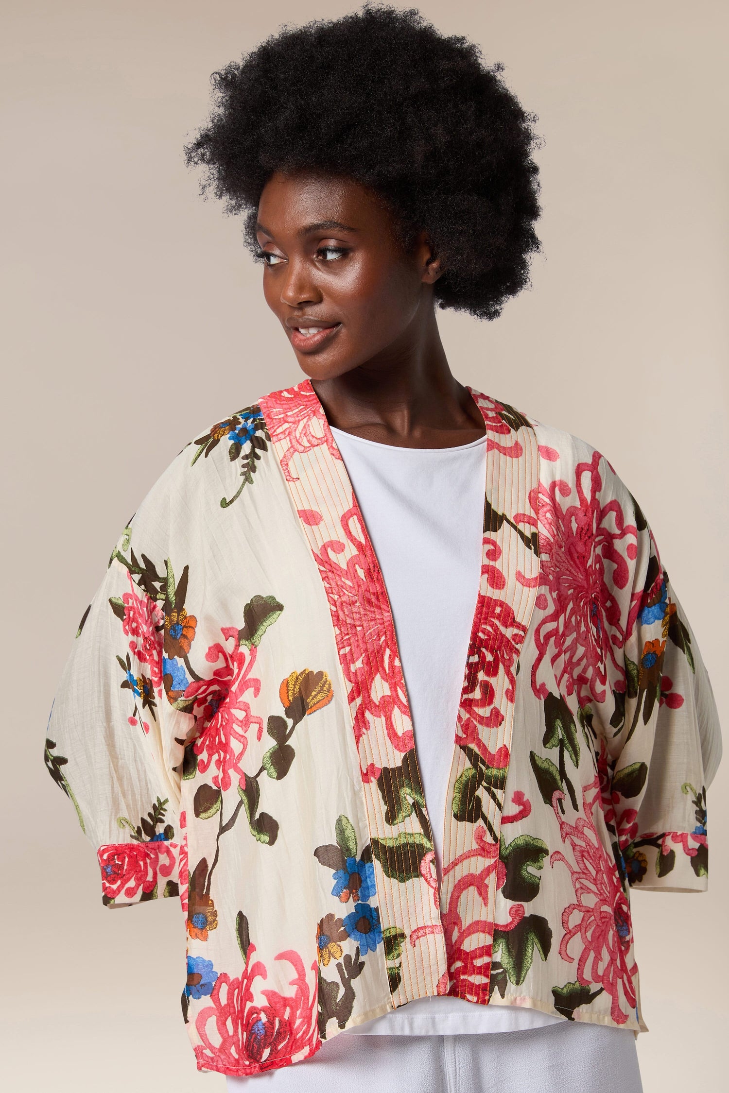 A black woman wearing a Chrysanthemum Kimono, a lightweight floral kimono jacket with an open front.