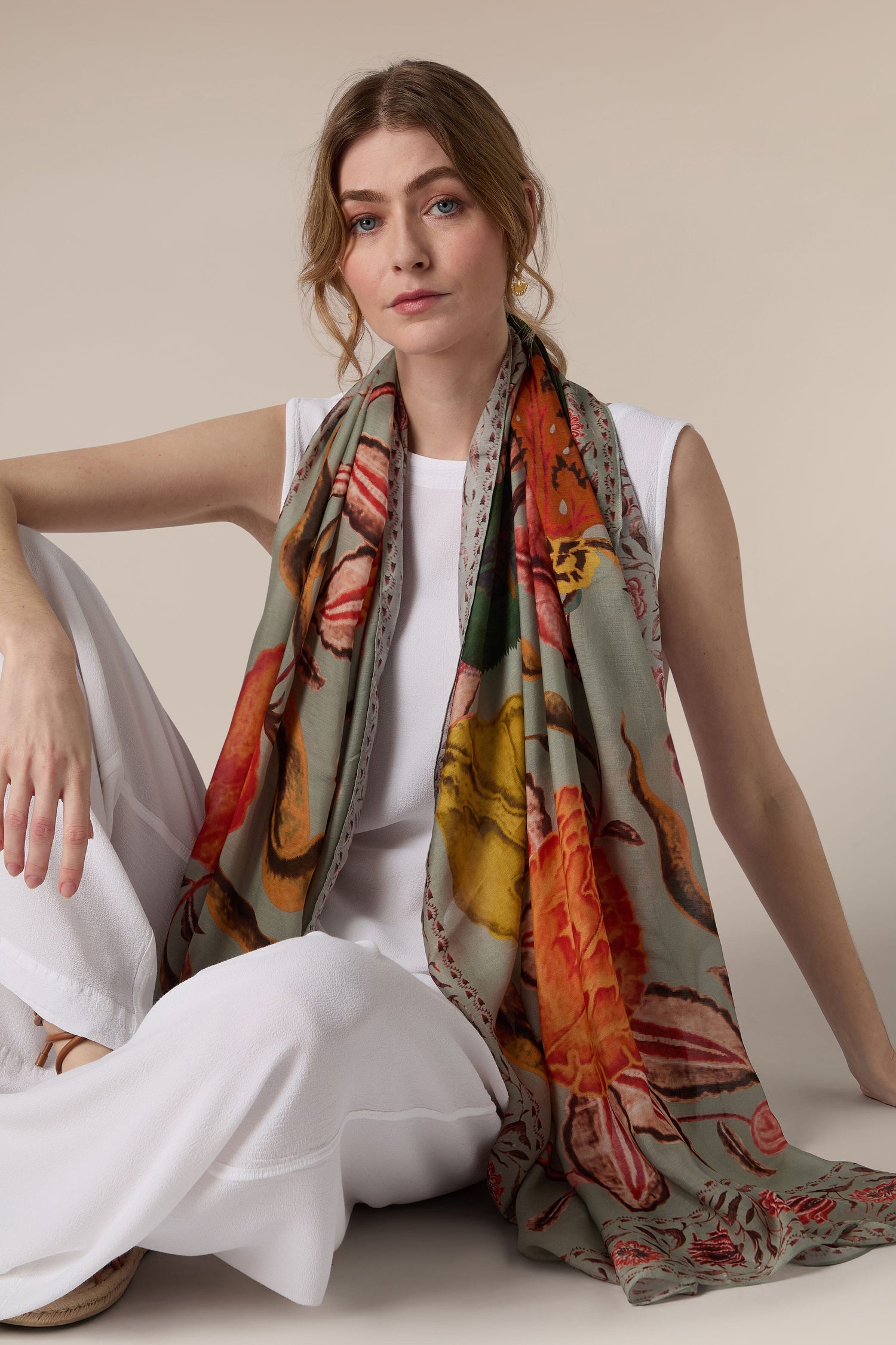 Woman in white attire posing with a hand-painted Joy Scarf.