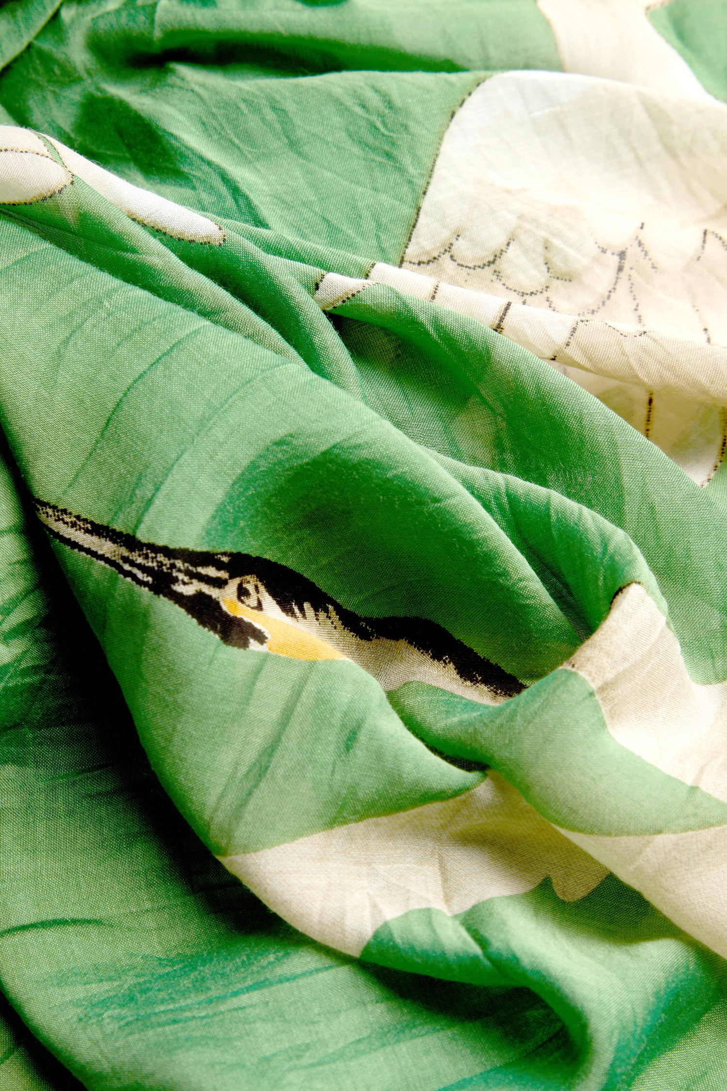 Close-up of the Stork Print Scarf, showcasing its green and white fabric with a woven bird design, making it a true statement piece.