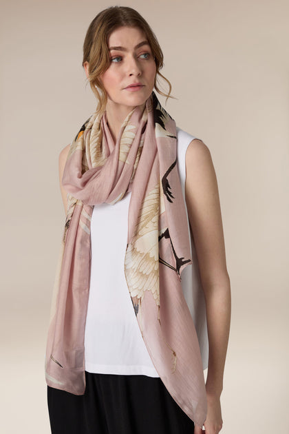 A woman wearing a white top and black skirt with an art deco Moon Phases Scarf looking to the side.